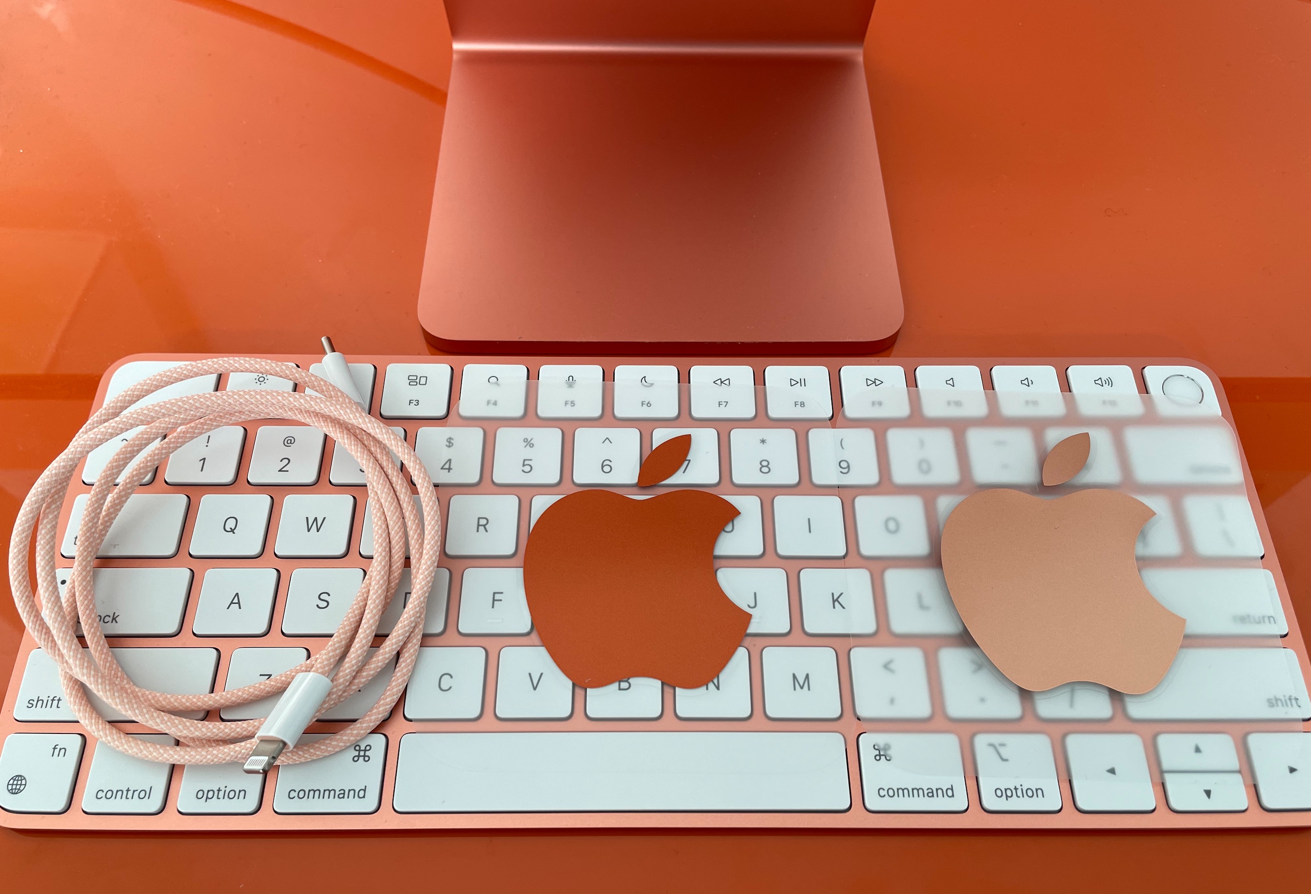 The color-coordinated orange Lightning cable and stickers, atop the orange Touch ID Magic Keyboard.
