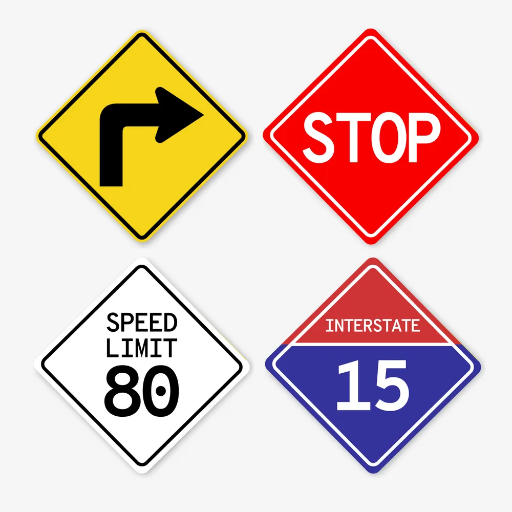 Four diamond-shaped road signs: a yellow right-turn warning sign, a red stop sign, a white speed limit 80 sign, and an Interstate 15 highway marker.